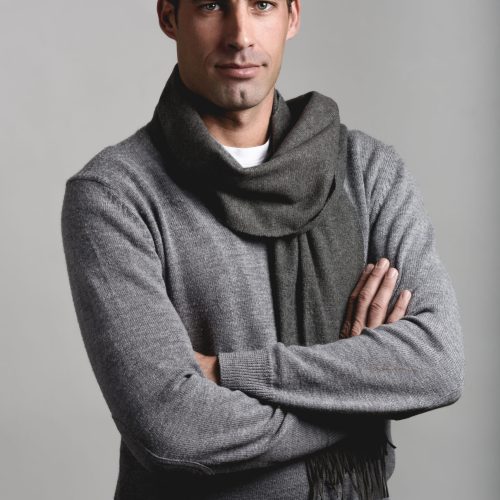 Handsome man wearing winter clothes smiling on white background. Young male with swater and scarf looking at camera. Studio shot