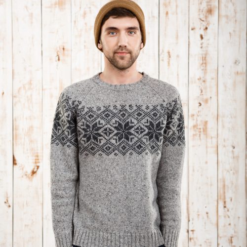 Young handsome man in sweater and hat looking at camera over wooden background. Copy space.